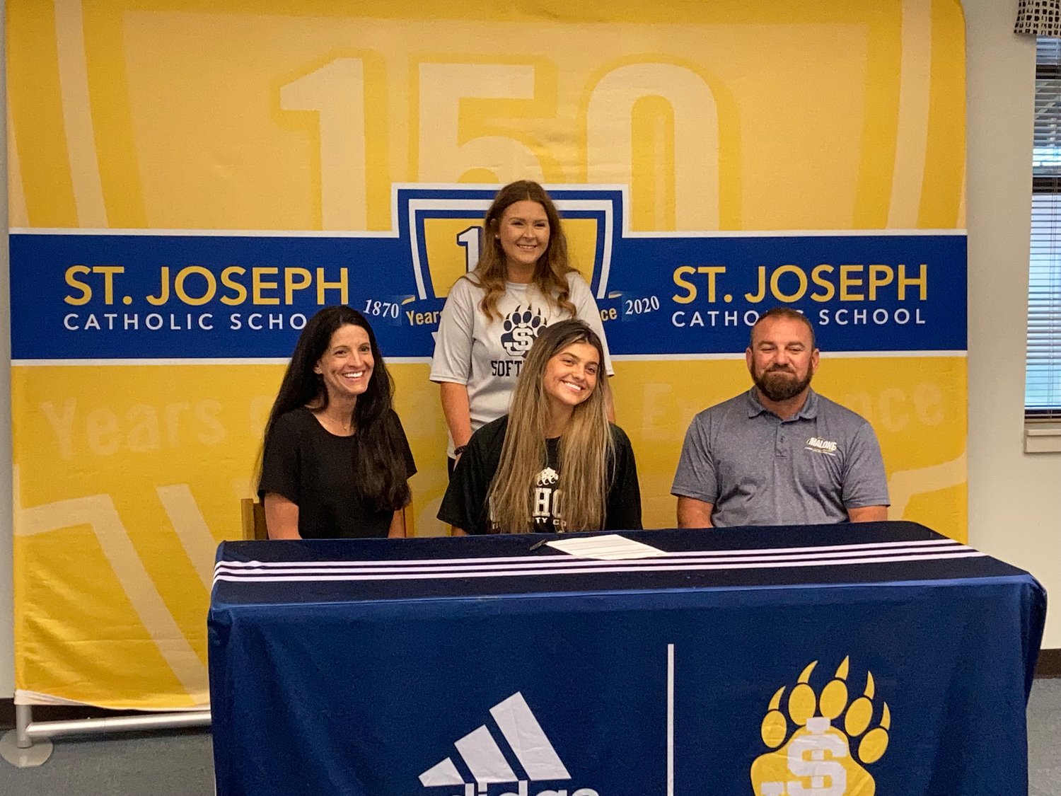 Pictured here are Edwards, center; Kelli Phillips, her mother, left; Dan Edwards, her father, right; and Danielle Poe, Bruin softball coach, standing behind Edwards.